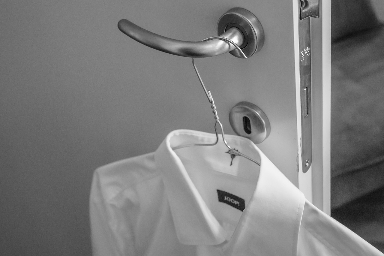 Белая рубашка на плечиках на ручке двери