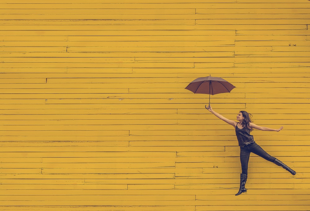 Девушка с зонтиком на фоне стены, как будто летит